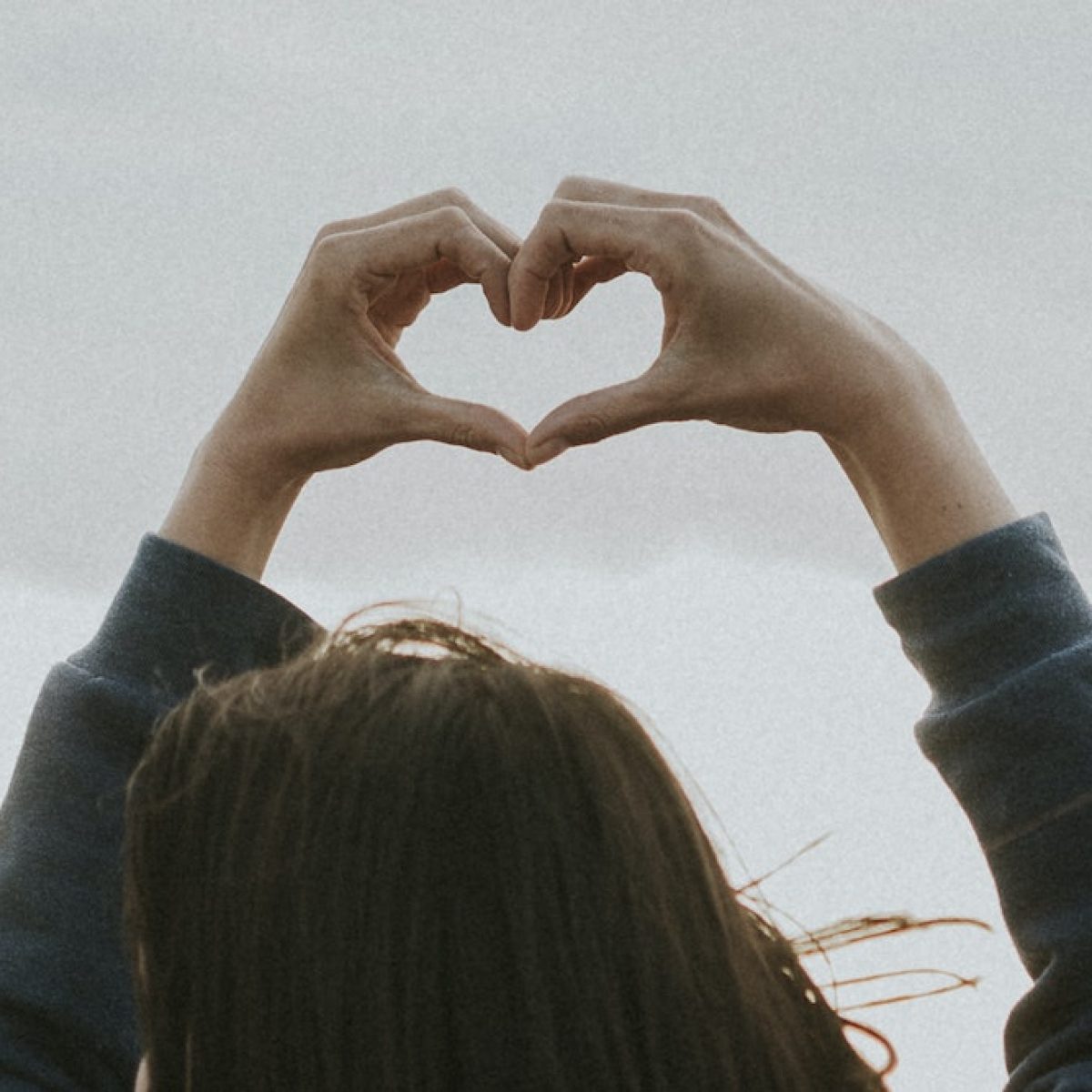 Friends making love heart hands at the beach